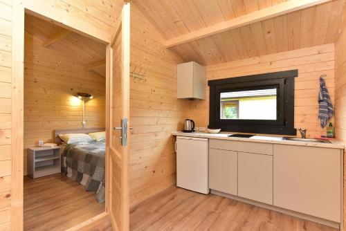 a kitchen in a wooden cabin with a bed at Nameliai Gulbės takas in Šventoji