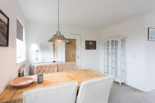 a dining room with a wooden table and white chairs at Hello Zeeland - Appartement Weststraat 14 in Domburg
