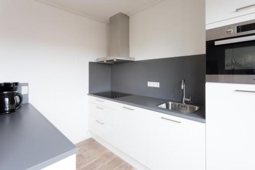 a white kitchen with white cabinets and a sink at Hello Zeeland - Appartement Weststraat 14 in Domburg