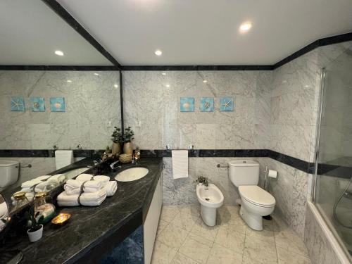 a bathroom with two sinks and a toilet and a tub at Lux Parede Ocean View in Parede
