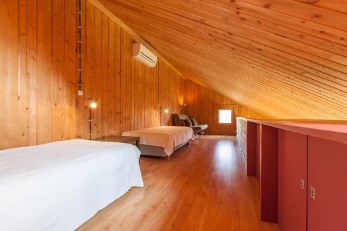 a attic bedroom with two beds and wooden walls at Casa da Piscina - Casas de Alem - Ecoturismo in Arcos de Valdevez