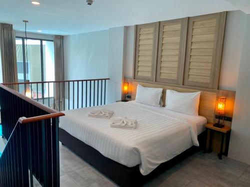 a bedroom with a bed with two towels on it at Atom Phuket Hotel -SHA Plus in Nai Yang Beach