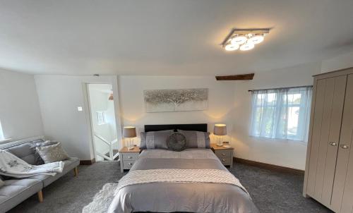 a bedroom with a large bed and a couch at Tollgate House - Luxury Cozy Cottage - HUGE Hot Tub - Alton Towers in Cheadle