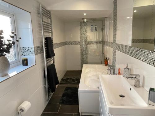 a white bathroom with a sink and a mirror at Tollgate House - Luxury Cozy Cottage - HUGE Hot Tub - Alton Towers in Cheadle