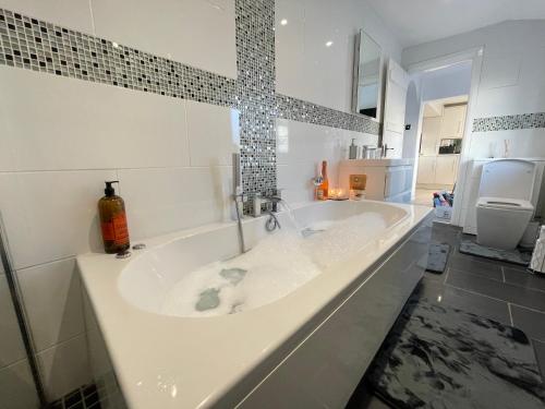 een groot wit bad in de badkamer bij Tollgate House - Luxury Cozy Cottage - HUGE Hot Tub - Alton Towers in Cheadle