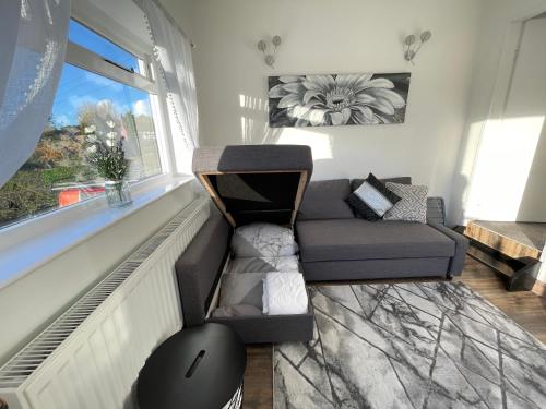 a living room with a couch and a window at Tollgate House - Luxury Cozy Cottage - HUGE Hot Tub - Alton Towers in Cheadle
