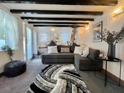 a living room with a couch and a rug at Tollgate House - Luxury Cozy Cottage - HUGE Hot Tub - Alton Towers in Cheadle