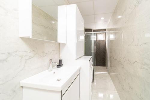 a white bathroom with a sink and a shower at Modern Flat near Beach in Antalya in Antalya