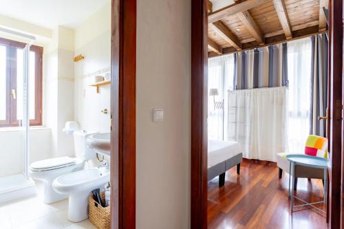 a bathroom with a sink and a toilet and a bedroom at Posada 3 Valles in Liérganes