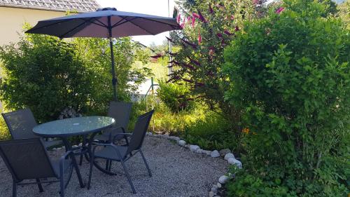 a table and chairs with an umbrella in a garden at CHILL&SLEEP Bad Ischl in Bad Ischl