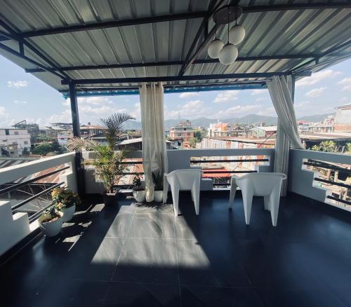 a balcony with white chairs and a view of a city at SunsetHomes A luxurious studio apartment in Imphal