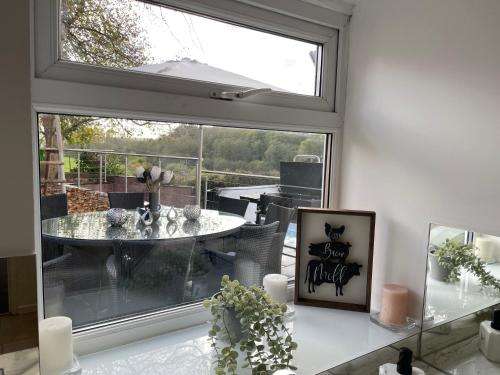 a dining room with a window and a table with a view at Tollgate House - Luxury Cozy Cottage - HUGE Hot Tub - Alton Towers in Cheadle