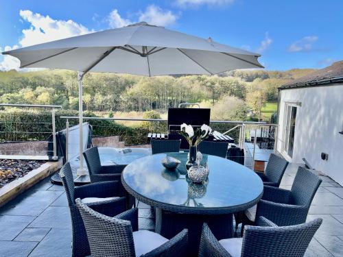 a table with chairs and an umbrella on a patio at Tollgate House - Luxury Cozy Cottage - HUGE Hot Tub - Alton Towers in Cheadle