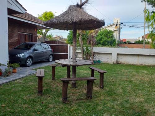 a table and bench with an umbrella in a yard at NECOCHEA DEPARTAMENTO TIPO LOFT 4 PAX in Necochea