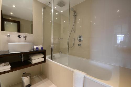 a bathroom with a shower and a sink and a tub at Park Grand London Kensington in London