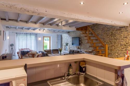 a kitchen with a sink and a living room at Gîte de charme à la campagne in Coësmes