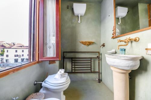 a bathroom with a sink and a toilet and a window at Easylife - Splendido appartamento con vista sul Naviglio Grande in Milan