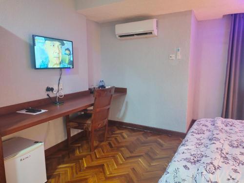 um quarto com uma secretária, uma cama e uma televisão em Serene Beach Resort em Dar es Salaam