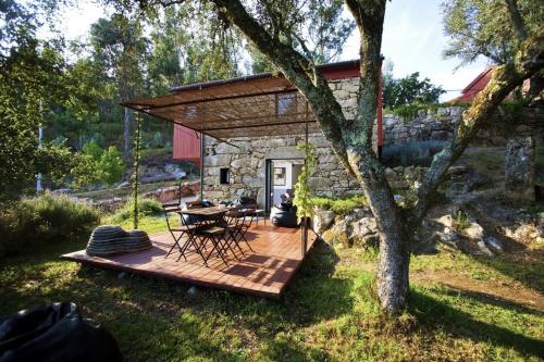 a wooden deck with a table and chairs in a yard at GoToGeres - Casa da Ramada - Sobrenatura in Arcos de Valdevez