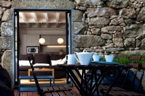 a table with bowls and plates on it in front of a stone wall at GoToGeres - Casa da Ramada - Sobrenatura in Arcos de Valdevez