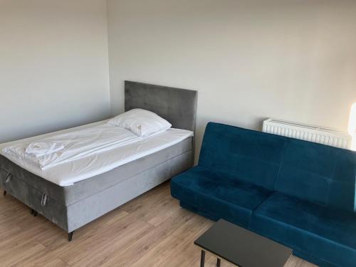 um quarto com uma cama e um sofá azul em JAB Apartament Przy Klinice Business & Family em Szczecin
