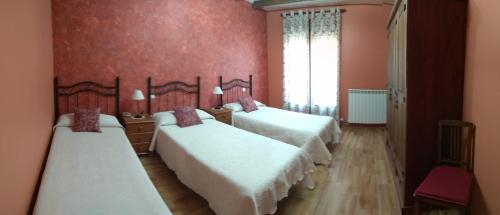 two beds in a room with red walls at LA QUEDADA DE NAVA in Nava del Rey
