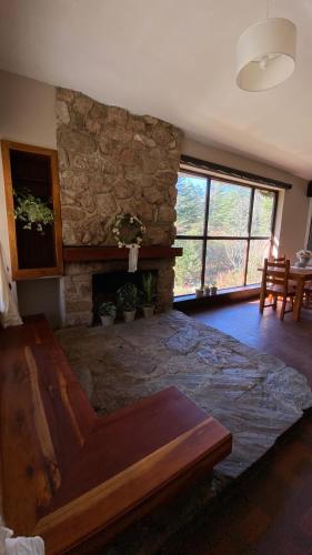 a living room with a stone wall and a fireplace at El gran roble in La Cumbrecita