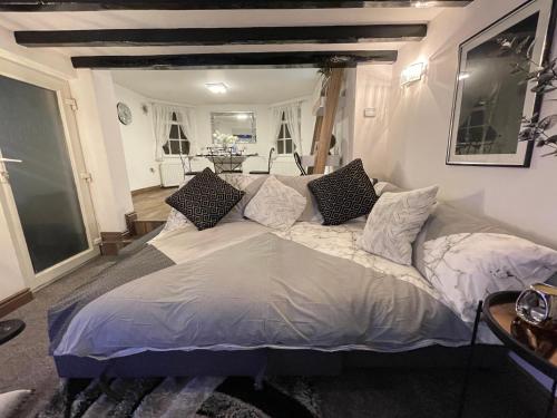 a bedroom with a large bed with pillows on it at Tollgate House - Luxury Cozy Cottage - HUGE Hot Tub - Alton Towers in Cheadle