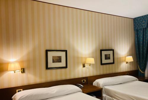 a hotel room with two beds and two lamps at Hotel Ghironi in La Spezia