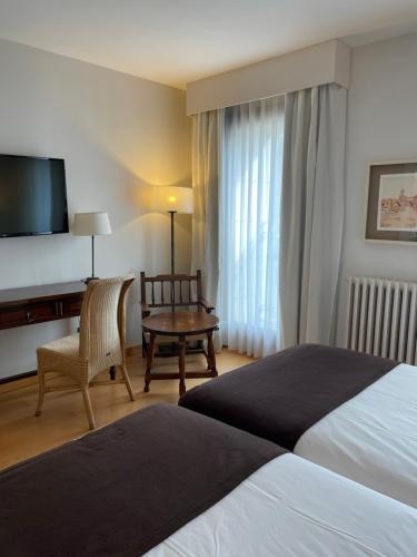a hotel room with a bed and a desk and a television at Parador de Puebla de Sanabria in Puebla de Sanabria