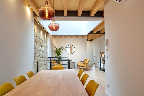 uma sala de jantar com uma mesa longa e cadeiras amarelas em Brito Capelo 183 em Matosinhos