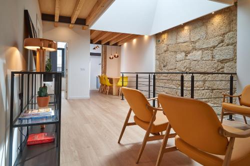Habitación con sillas, mesa y pared de piedra. en Brito Capelo 183, en Matosinhos