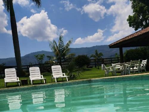 a group of white chairs and a swimming pool at Contempla Joanópolis in Joanópolis