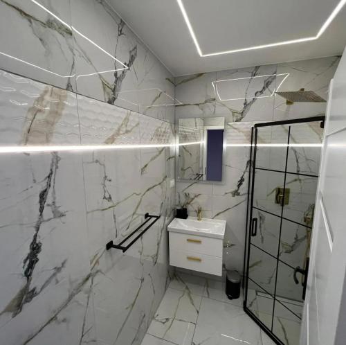 y baño con paredes de mármol blanco y ducha. en Apartamenty nad jeziorem Białym KA-BOATS en Augustów