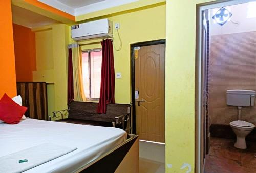 een slaapkamer met een bed, een toilet en een deur bij Trinayani Stay - 3 min Walk to Temple in Tarapith