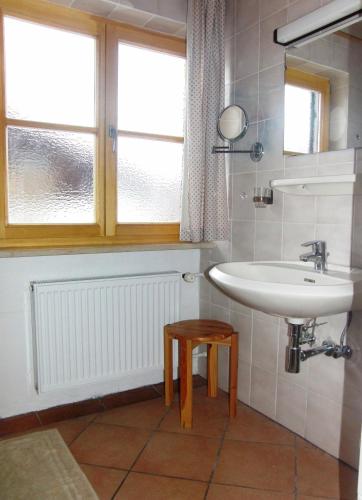 a bathroom with a sink and a window and a stool at Haus Christoph in Bad Wiessee