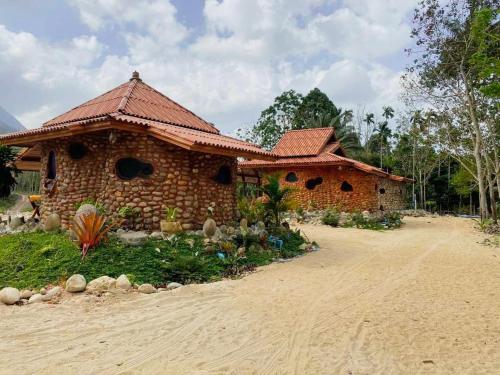 un edificio de ladrillo con techo en un camino de tierra en ลีลา โฮมสเตย์ Leela Homestay, en Ban Tha Phae