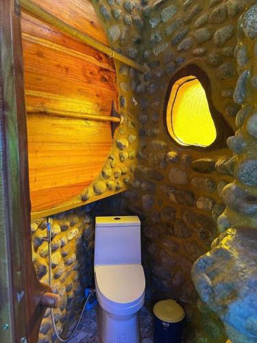 a small bathroom with a toilet in a stone wall at ลีลา รีสอร์ท Leela Resort in Ban Tha Phae