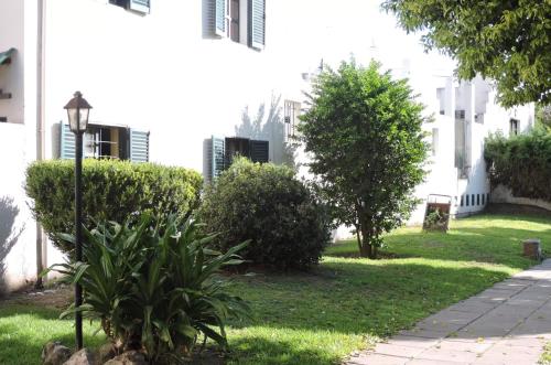un patio verde con arbustos y un edificio en Castillo del Lago Carlos Paz - Solo Familiar en Villa Carlos Paz