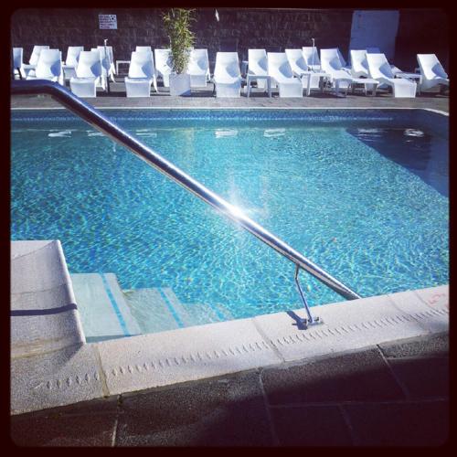 a large swimming pool with white chairs in a hotel at Norfolk Hotel in Saint Helier Jersey