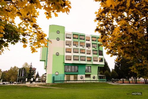 un bâtiment vert et blanc dans un parc dans l'établissement MC Hotel, à Žalec