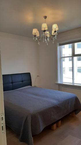 a bedroom with a bed with a blue blanket and a chandelier at Next Apartment Bergstadastræti in Reykjavík