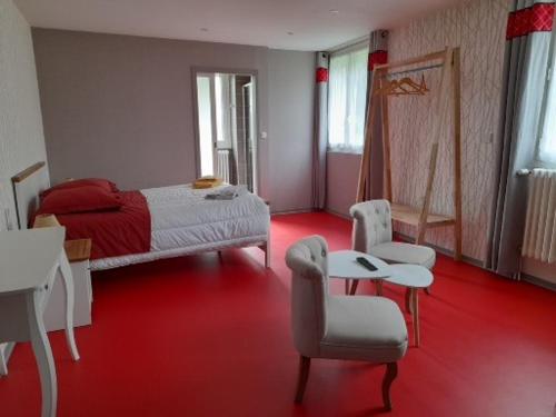 ein Schlafzimmer mit einem Bett und Stühlen sowie einem roten Boden in der Unterkunft CH MALAVETULA in Chastel-Nouvel
