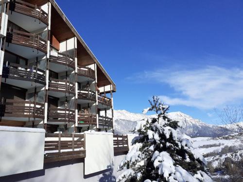 un bâtiment dans la neige avec un arbre recouvert de neige dans l'établissement Studio au Sauze avec balcon, parking et équipements tout confort - FR-1-165A-114, à Enchastrayes