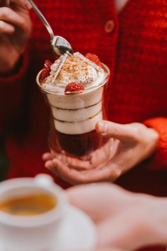 a person holding a dessert in a glass dish with a spoon at PURO Warszawa Centrum in Warsaw