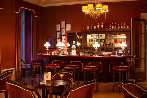 a bar in a restaurant with red walls and stools at Grand Hotel Beau Rivage Interlaken in Interlaken