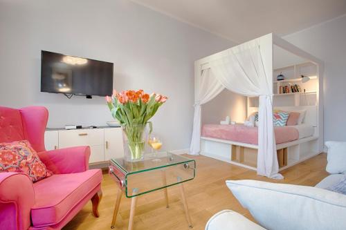una sala de estar con una cama y un jarrón de flores en Tyzenhauz Apartments Kazimierz, en Cracovia