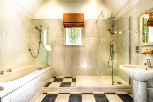 a bathroom with a tub shower and a sink at Mansion House Hotel in Elgin