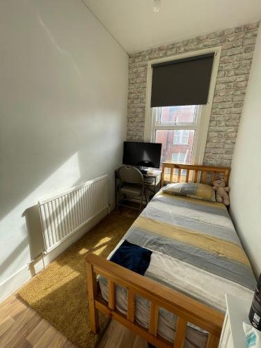 um quarto com uma cama, uma secretária e uma janela em Beautiful 3 bed apartment in Cricklewood em Londres