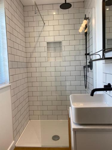 uma casa de banho com um lavatório e um chuveiro com azulejos brancos. em Old Town Oasis em Eastbourne